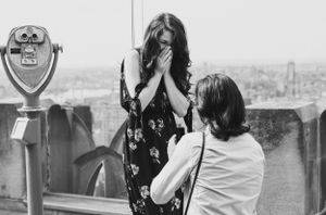 Black and white capture of an emotional marriage proposal moment at a city observation deck.