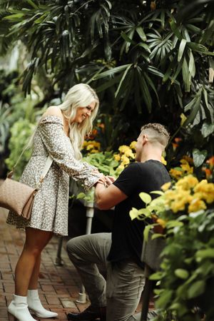 Marriage proposal scene in a botanical garden with palm trees and yellow flowers.