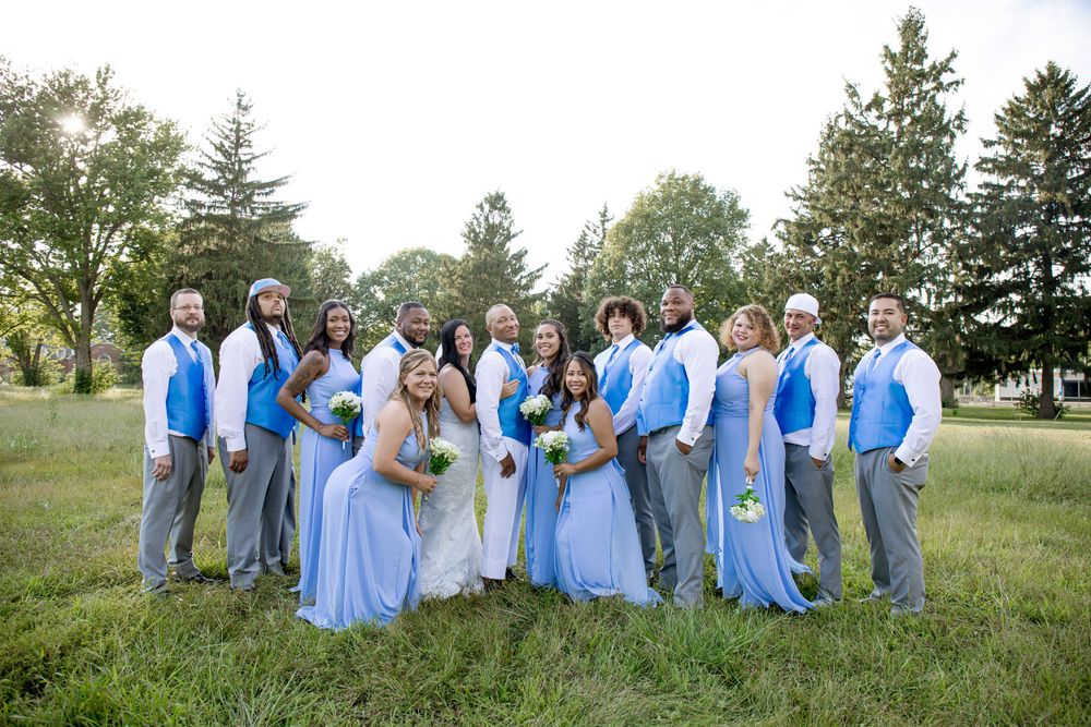 Wedding party arranged in casual group photo wearing coordinated blue and grey attire.