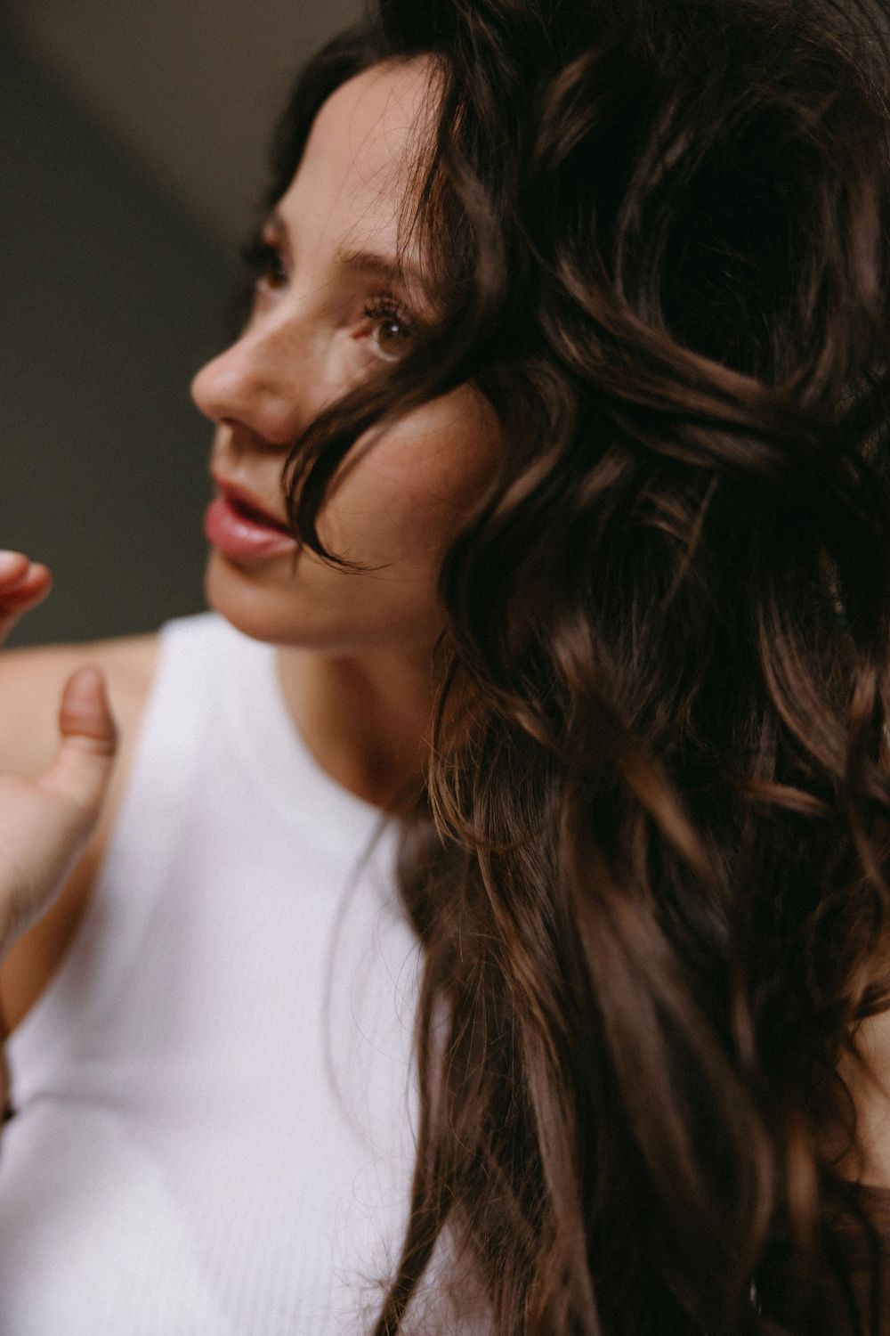 Artistic close-up portrait showing long wavy hair and soft natural lighting.