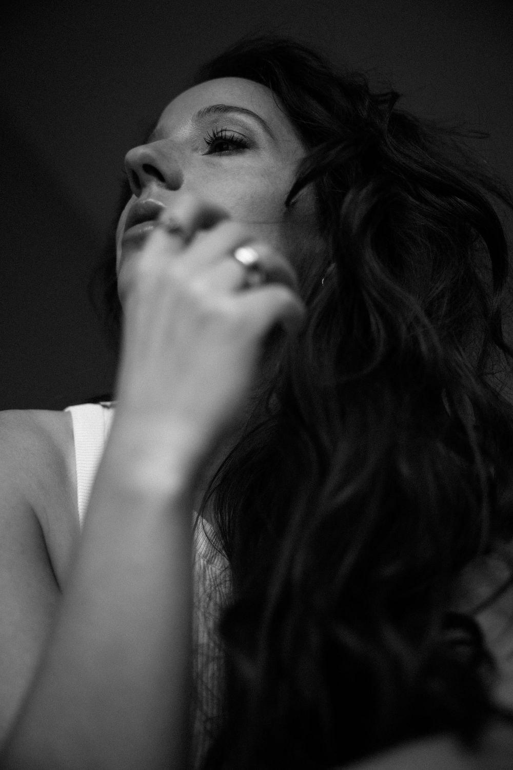 Dramatic black and white profile portrait with hand gesture and flowing hair.