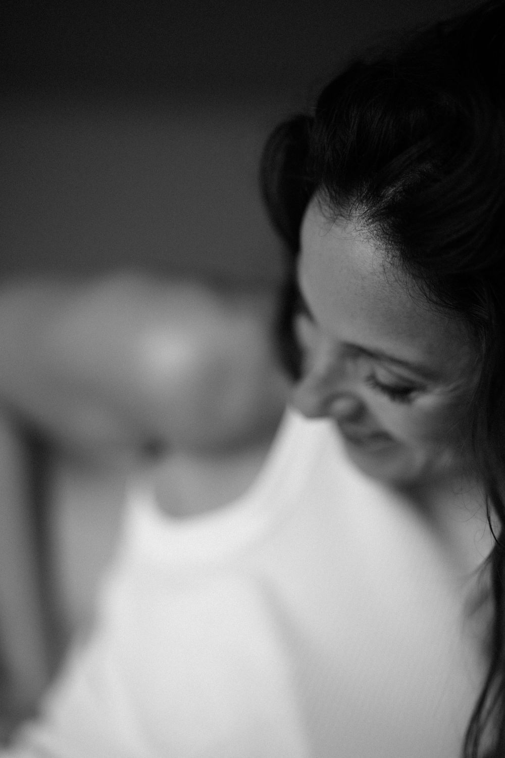 Intimate black and white portrait capturing a gentle downward glance and natural smile.