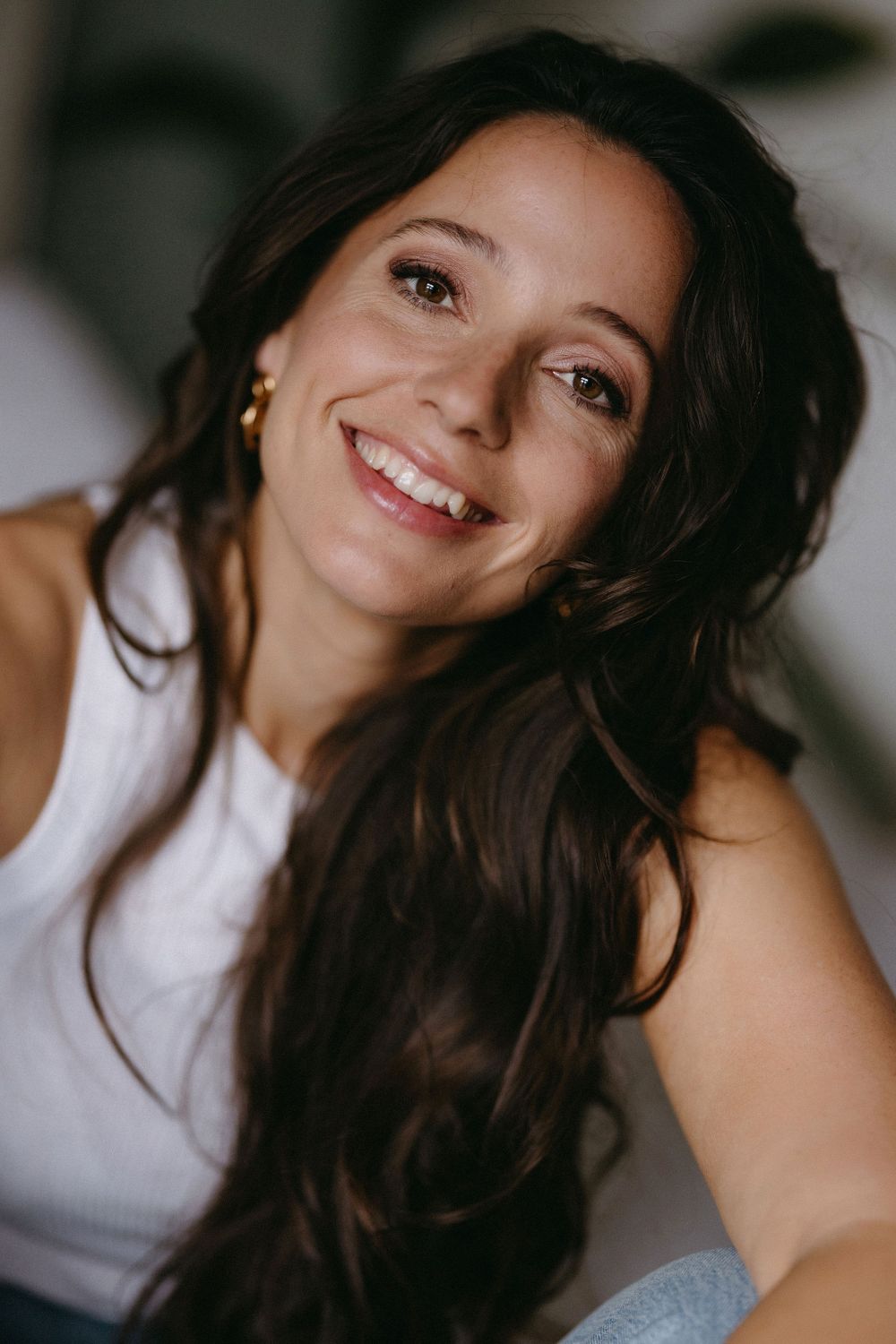 Portrait capturing genuine joy and warmth in natural lighting with long dark hair.