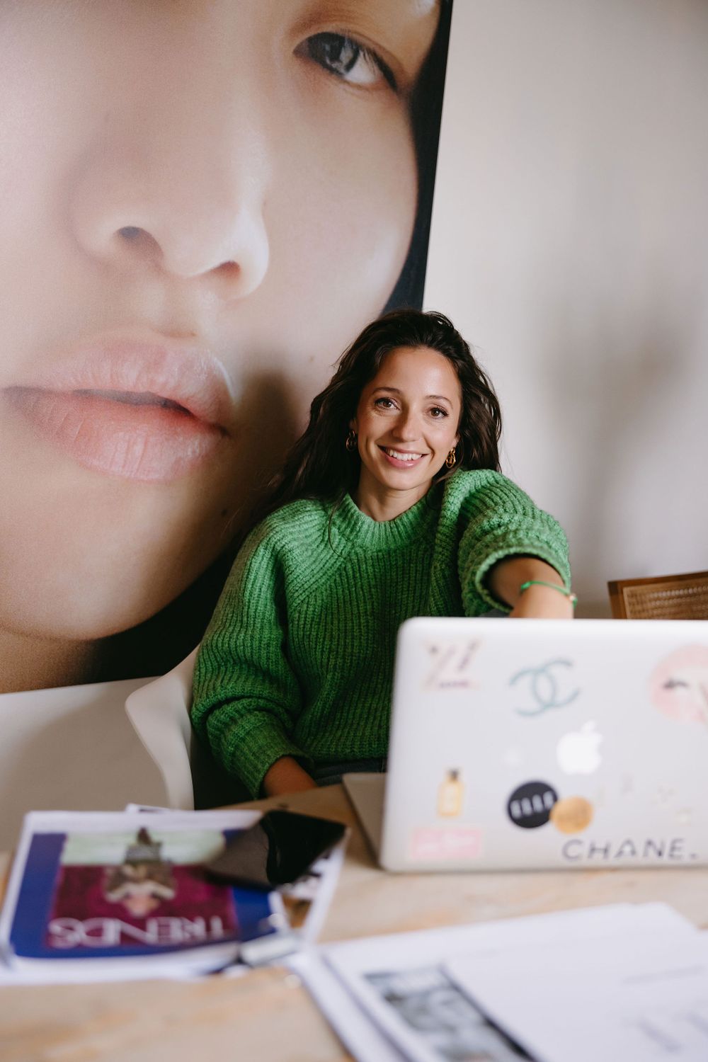 Creative workspace setup with laptop and fashion-themed wall art.