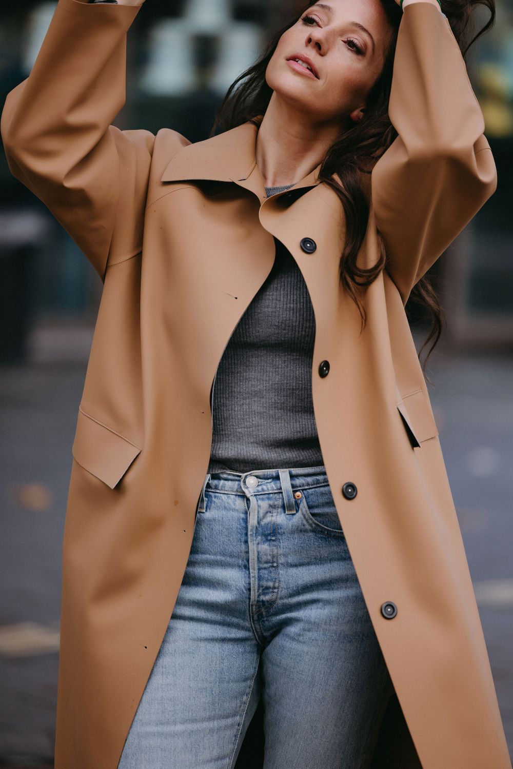 Close up of camel coat paired with grey sweater and classic blue jeans.