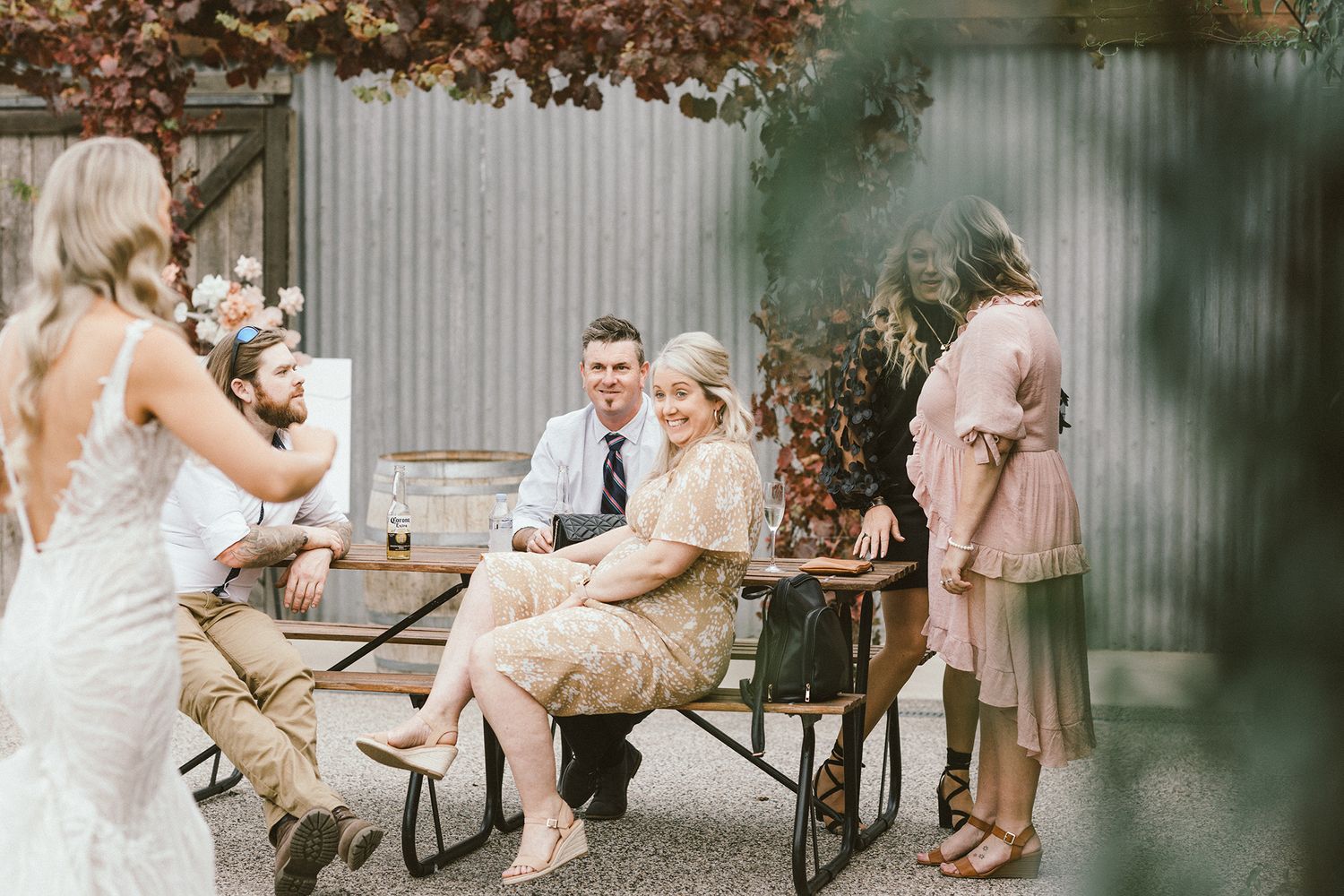 Wedding reception guests seated at long tables under rustic outdoor decor.