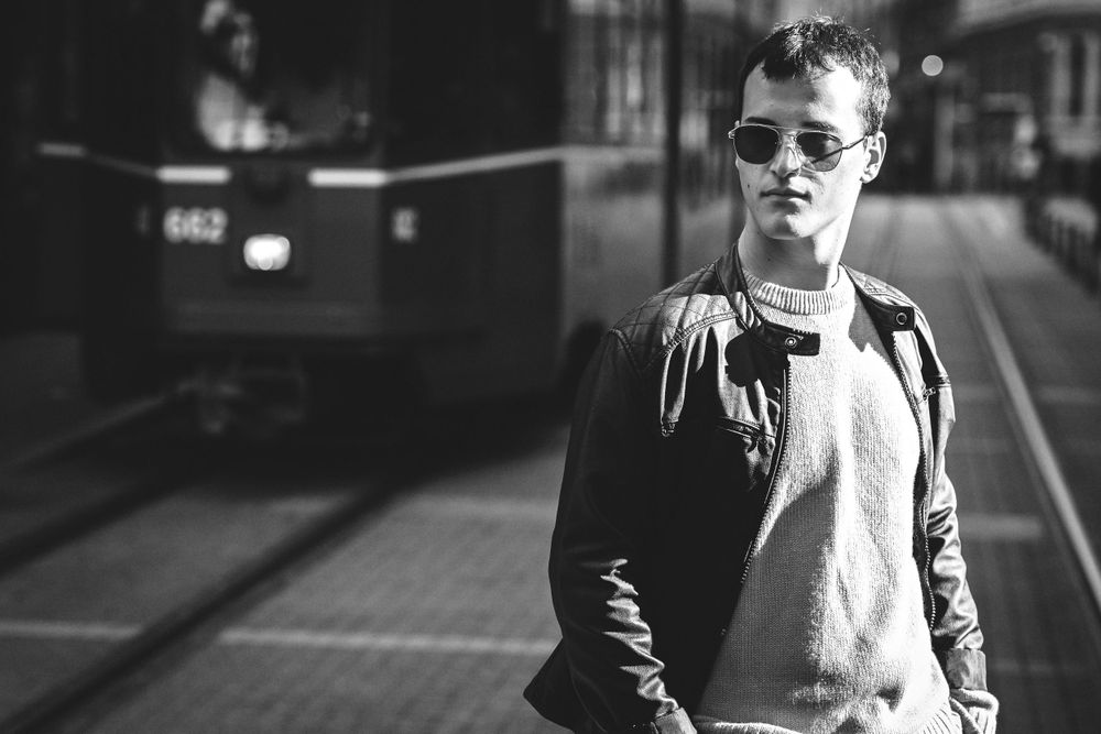 Black and white urban portrait with person in casual wear near train tracks.