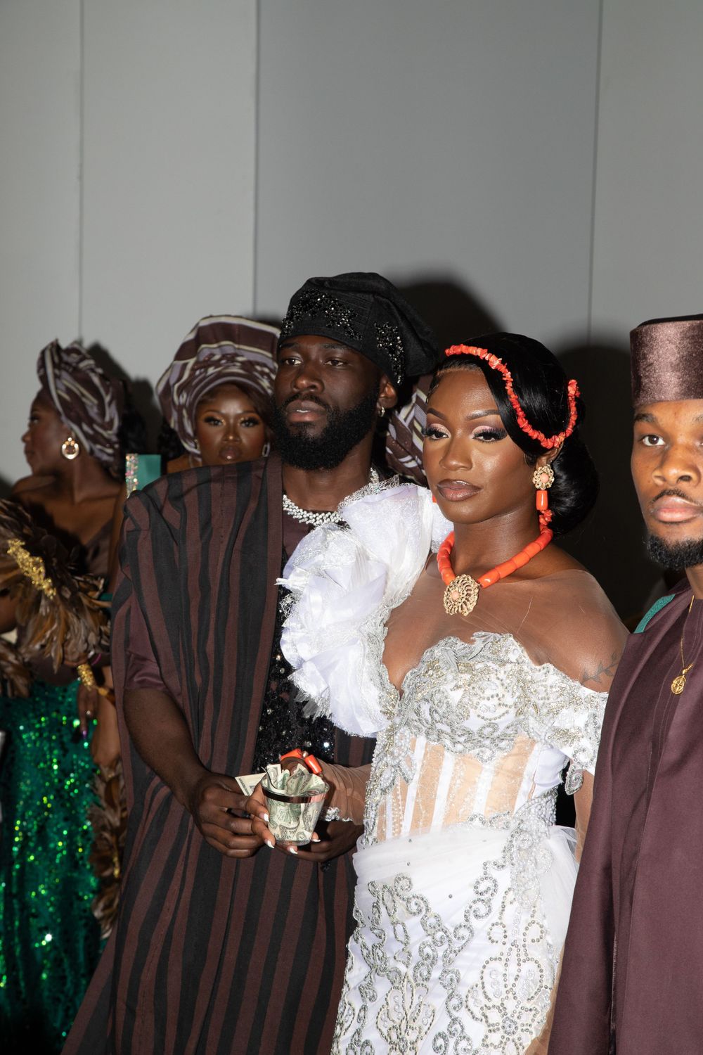 Wedding party members posing together in traditional African attire against a light background.