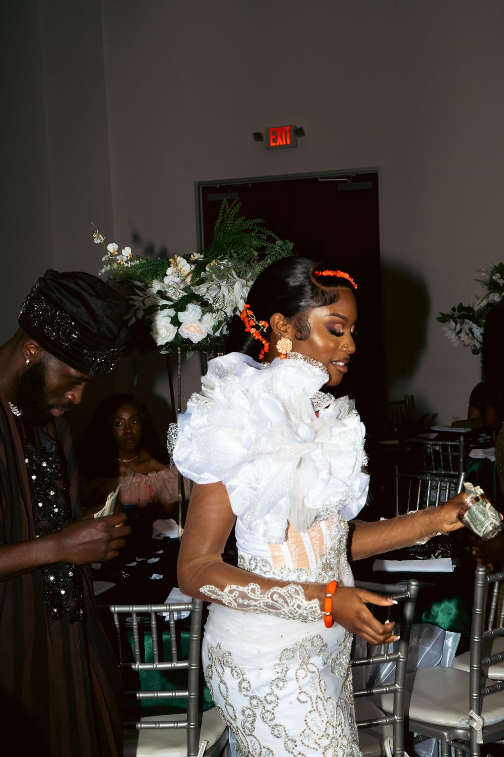 A bride in a white lace dress celebrating with guests at a wedding reception.