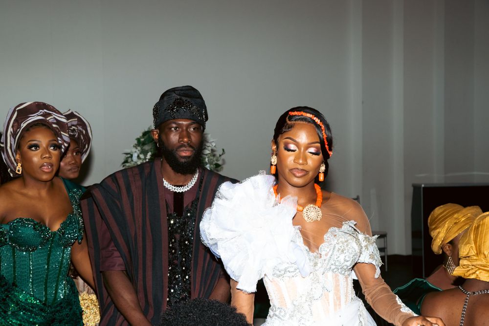 Wedding party members in coordinated traditional attire posing together at a reception.