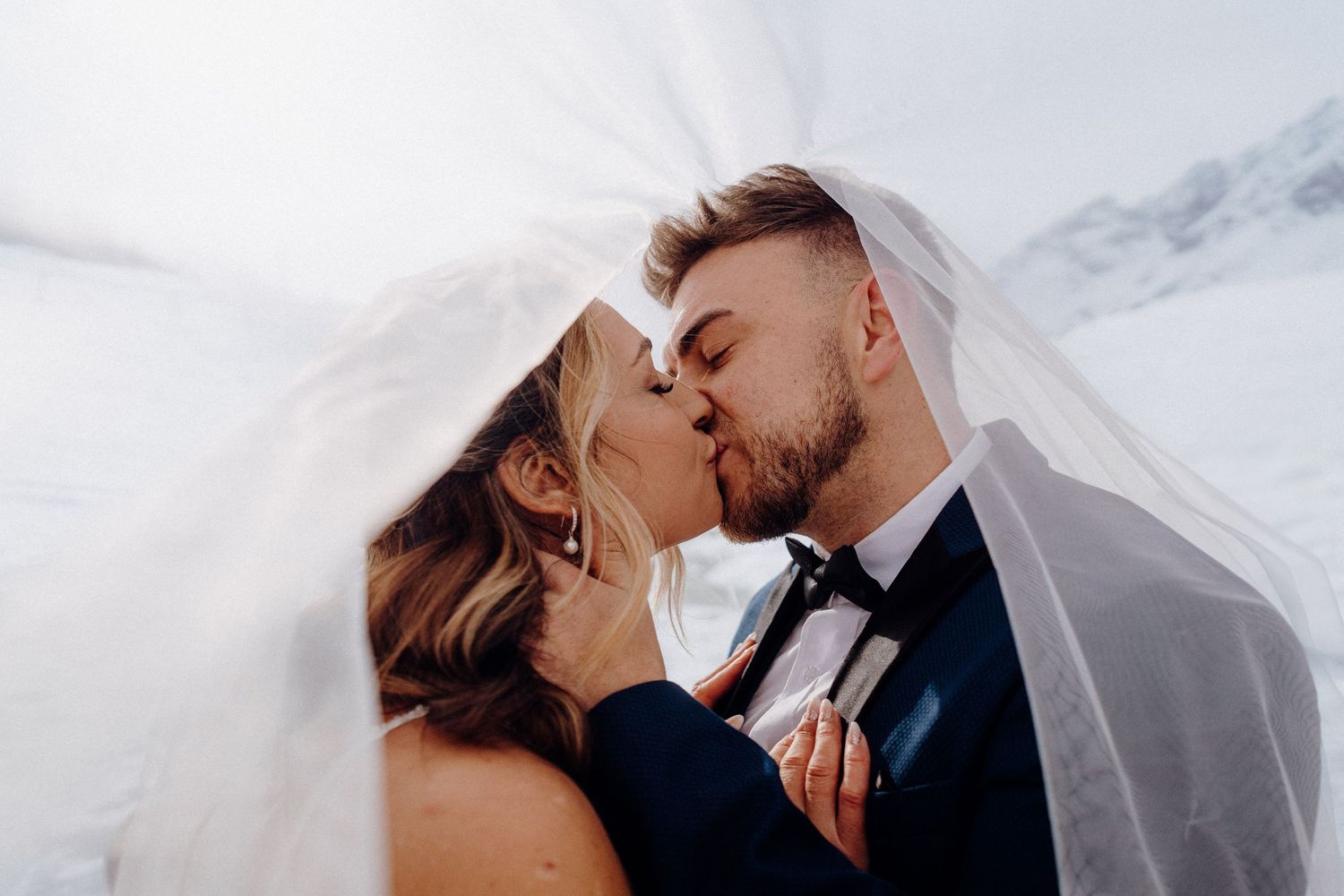A romantic kiss under a wedding veil in an intimate close-up shot.
