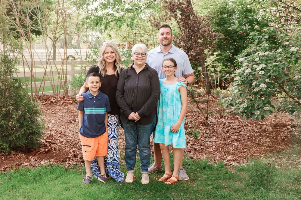 Family group photo taken in a wooded garden setting with natural landscaping.