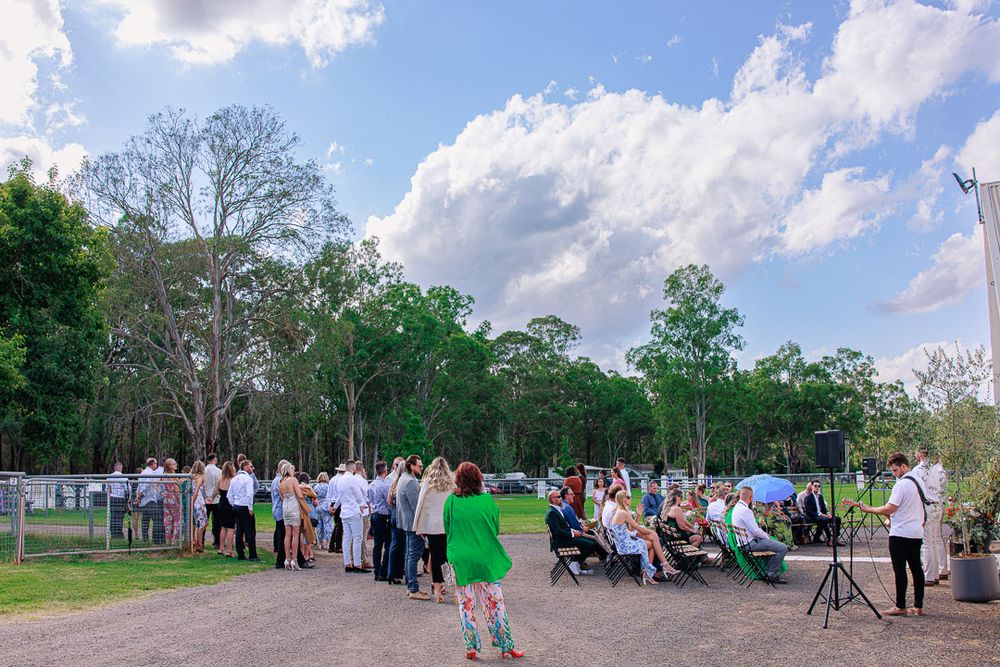 Panoramic view of an outdoor wedding venue with white chairs and natural forest backdrop.
