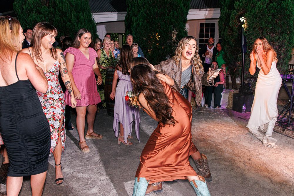 Wedding guests dancing in formal attire at outdoor evening reception.