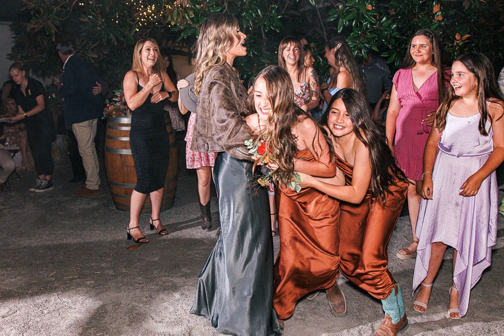 Large group of wedding guests dancing together at outdoor evening celebration.