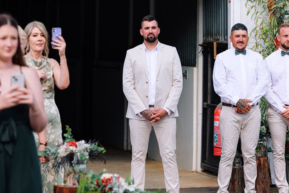 Wedding party members in white attire pose together during outdoor celebration.