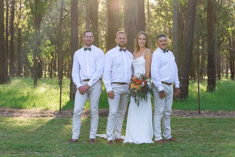 Formal wedding party portrait with bride and groomsmen in all white attire.