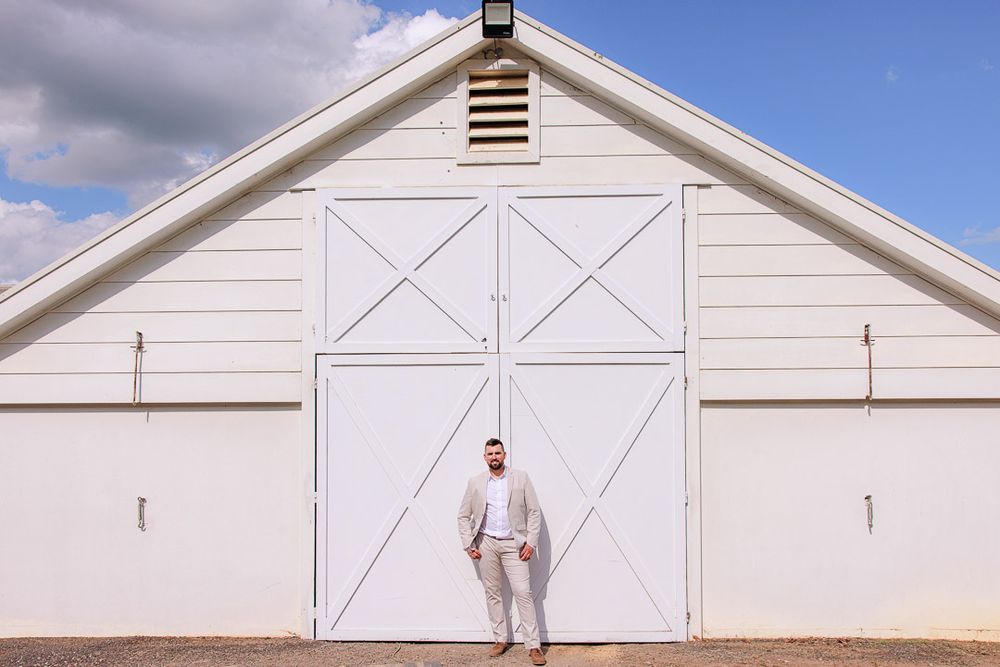 Minimalist white barn exterior with X-pattern doors creates elegant wedding venue backdrop.