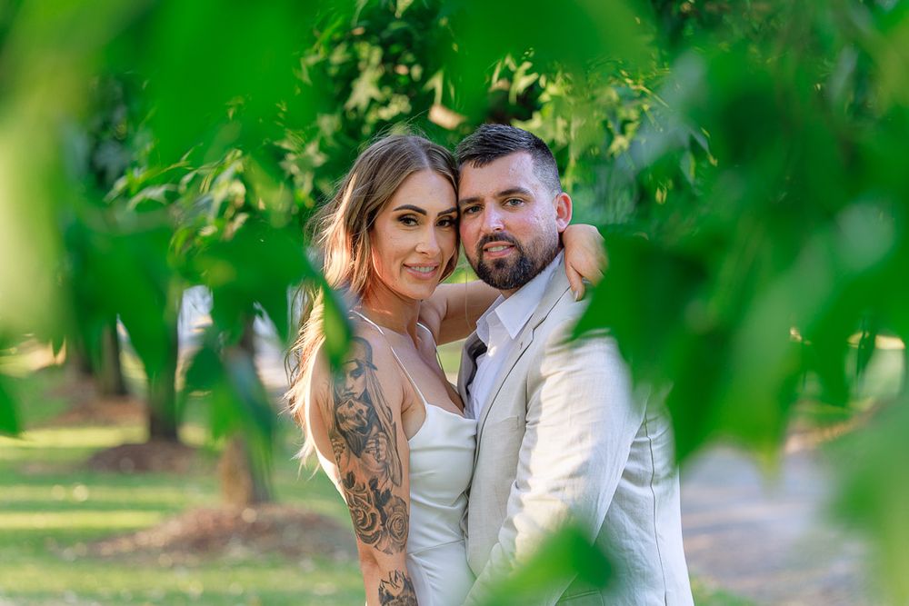 Couple shares tender moments during their wedding photoshoot in a lush green forest setting.