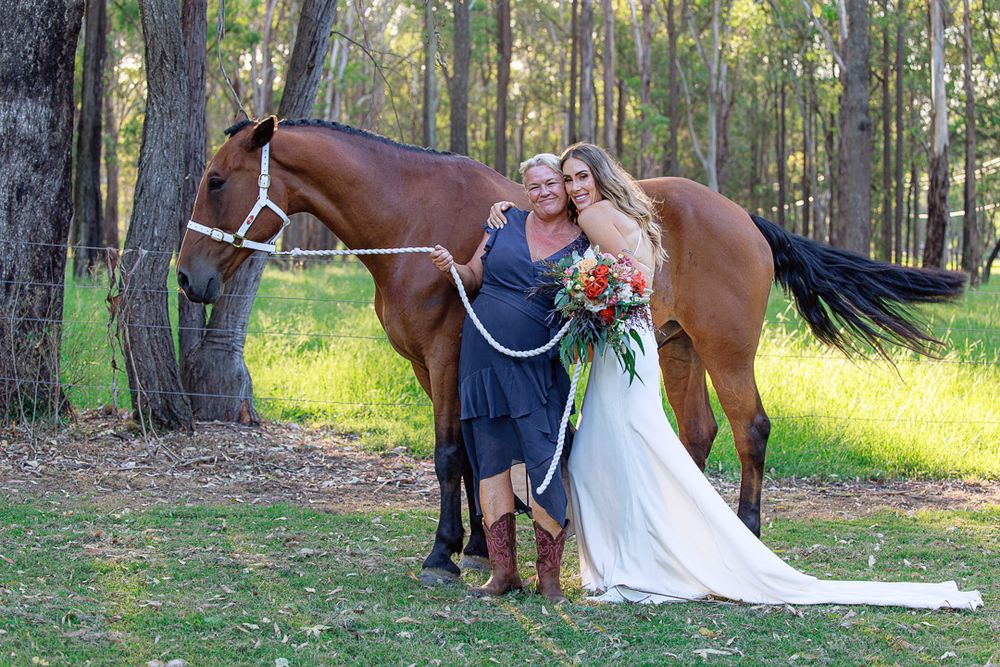 Wedding photography session in a forest featuring a brown horse and elegant white dress.