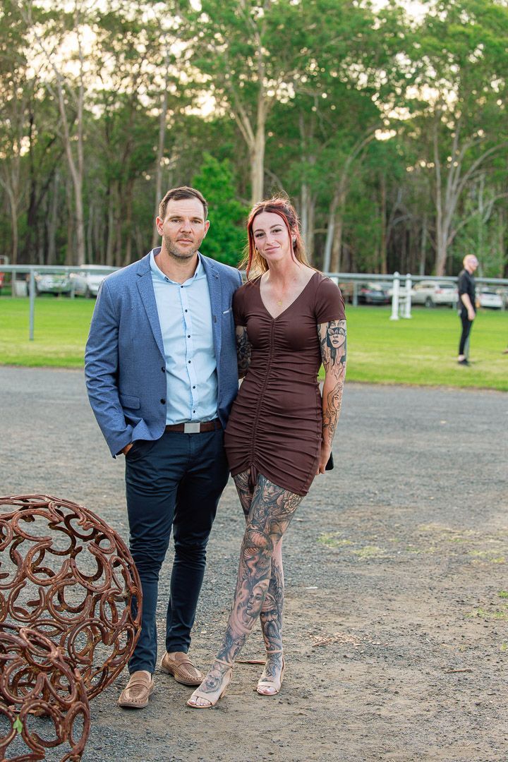 Outdoor gathering space with rustic metal sculpture and trees in background.