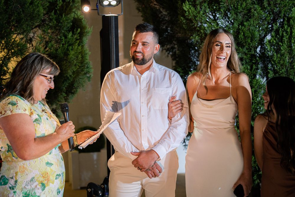 Guests enjoying themselves at an outdoor evening celebration with garden backdrop.
