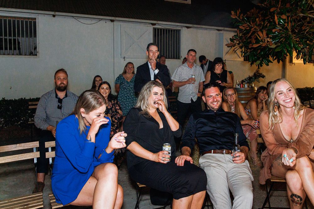 Guests mingle and dance at an outdoor evening reception with garden lighting.