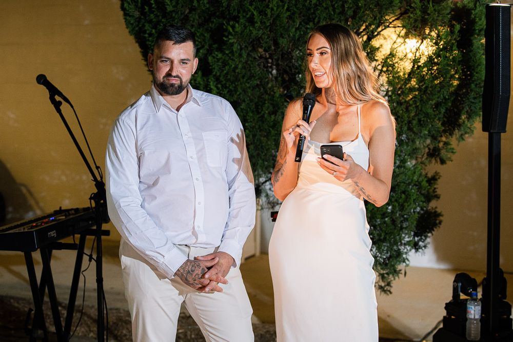 Wedding guests checking their phones while standing outside in the evening garden setting.