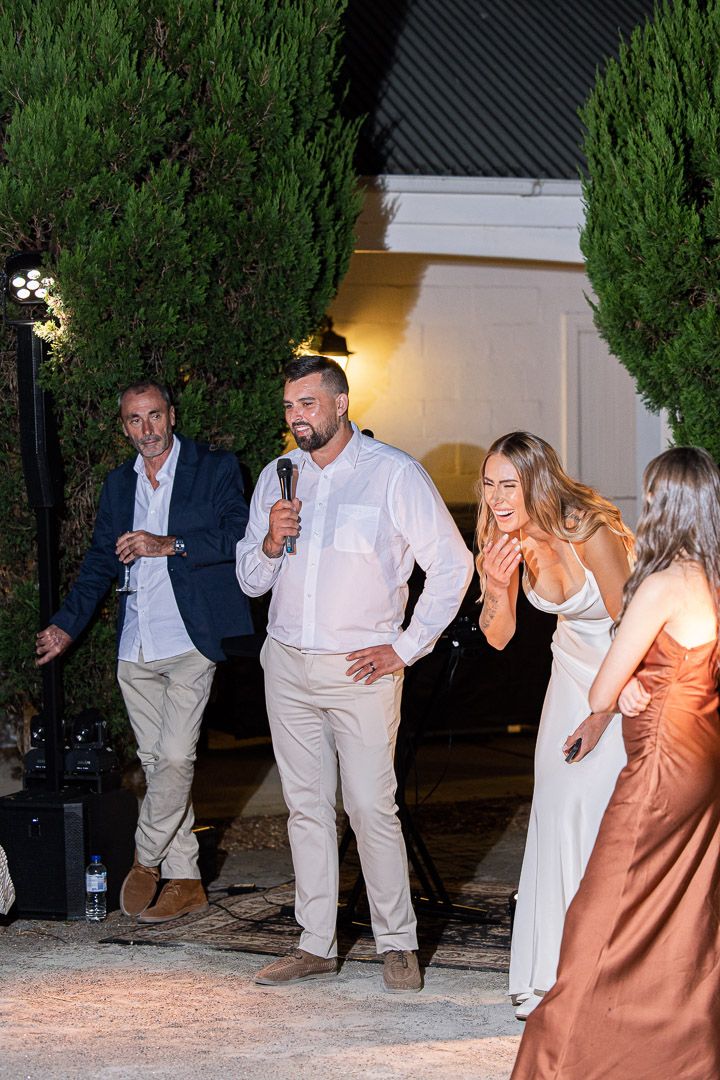 Group dancing energetically at an outdoor evening wedding reception.