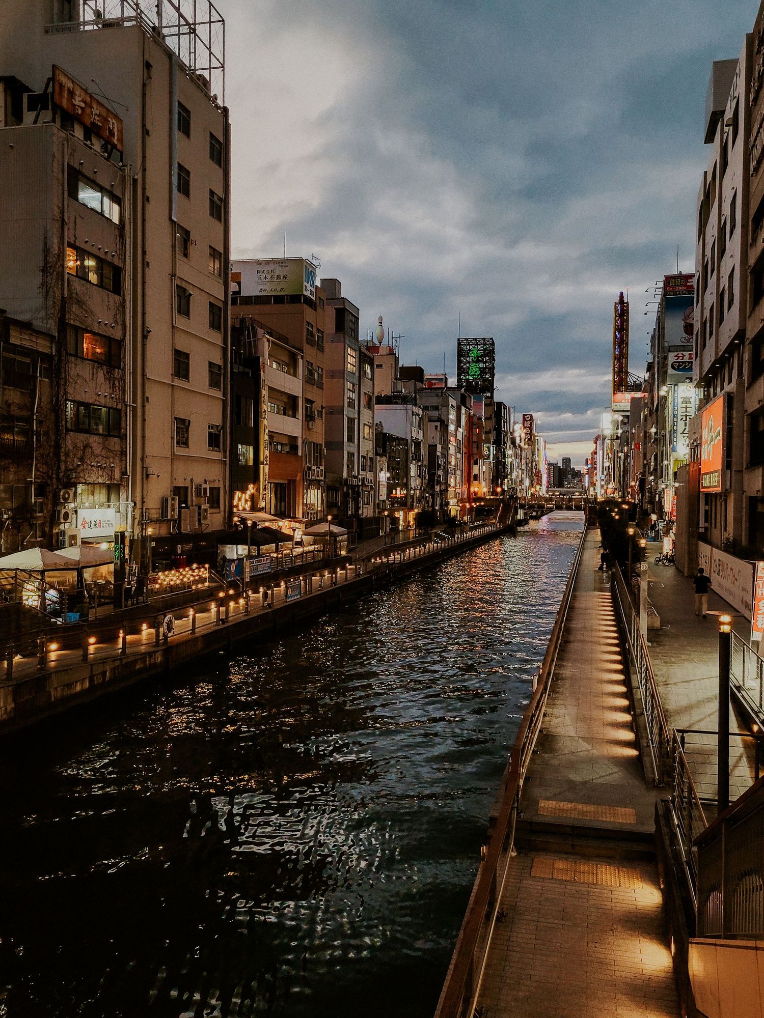 a canal of water in Japan surrounded by buildings and lights at dusk