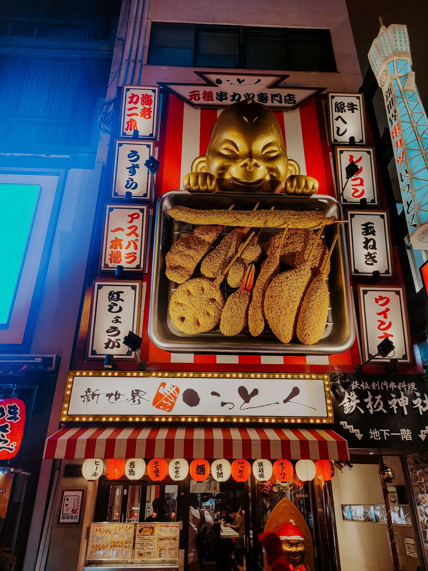 giant fried food ad on the top of a door with a gold baby looking at the food, Osaka, Japan