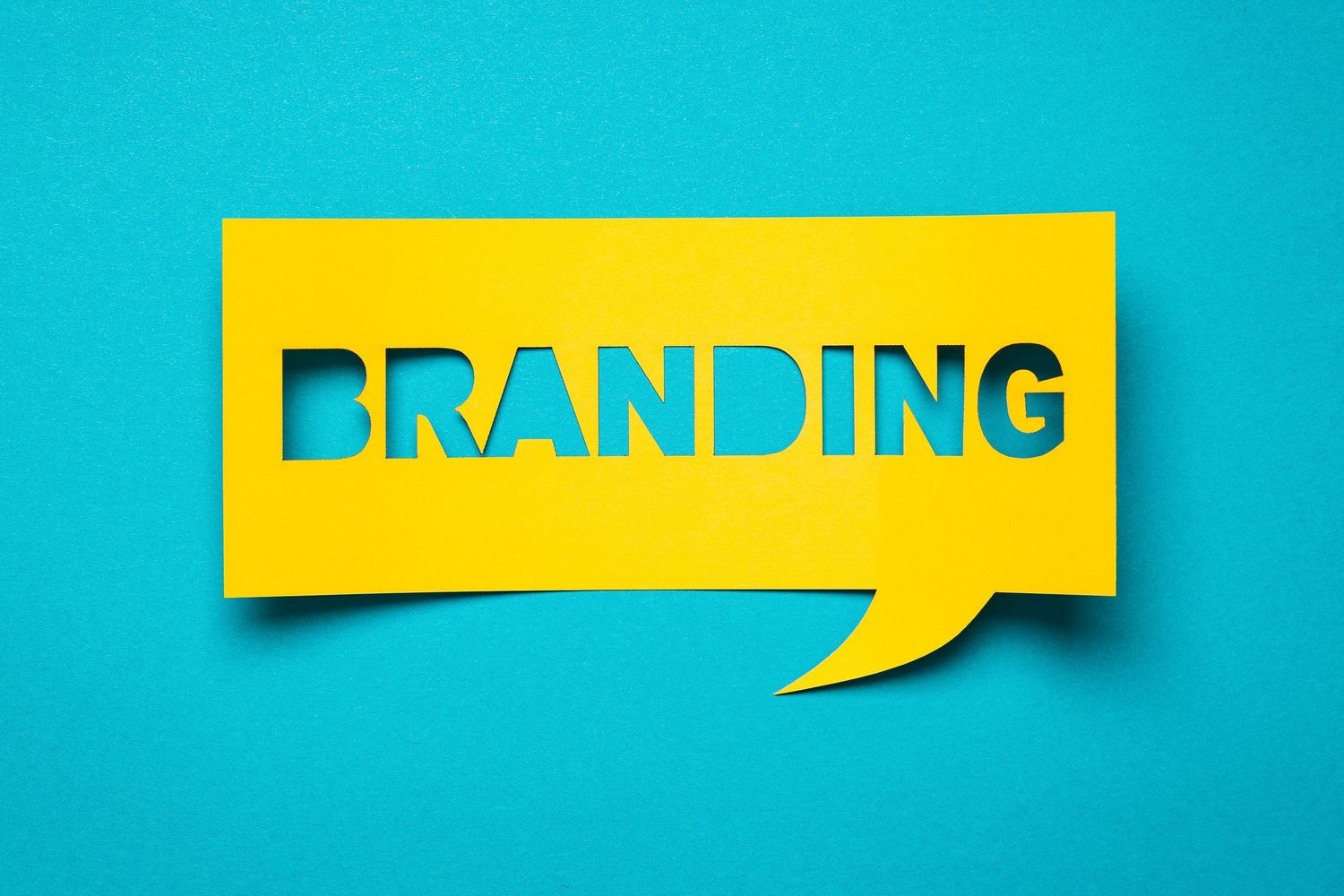 Yellow paper speech bubble with the word 'Branding' cut out on turquoise background.