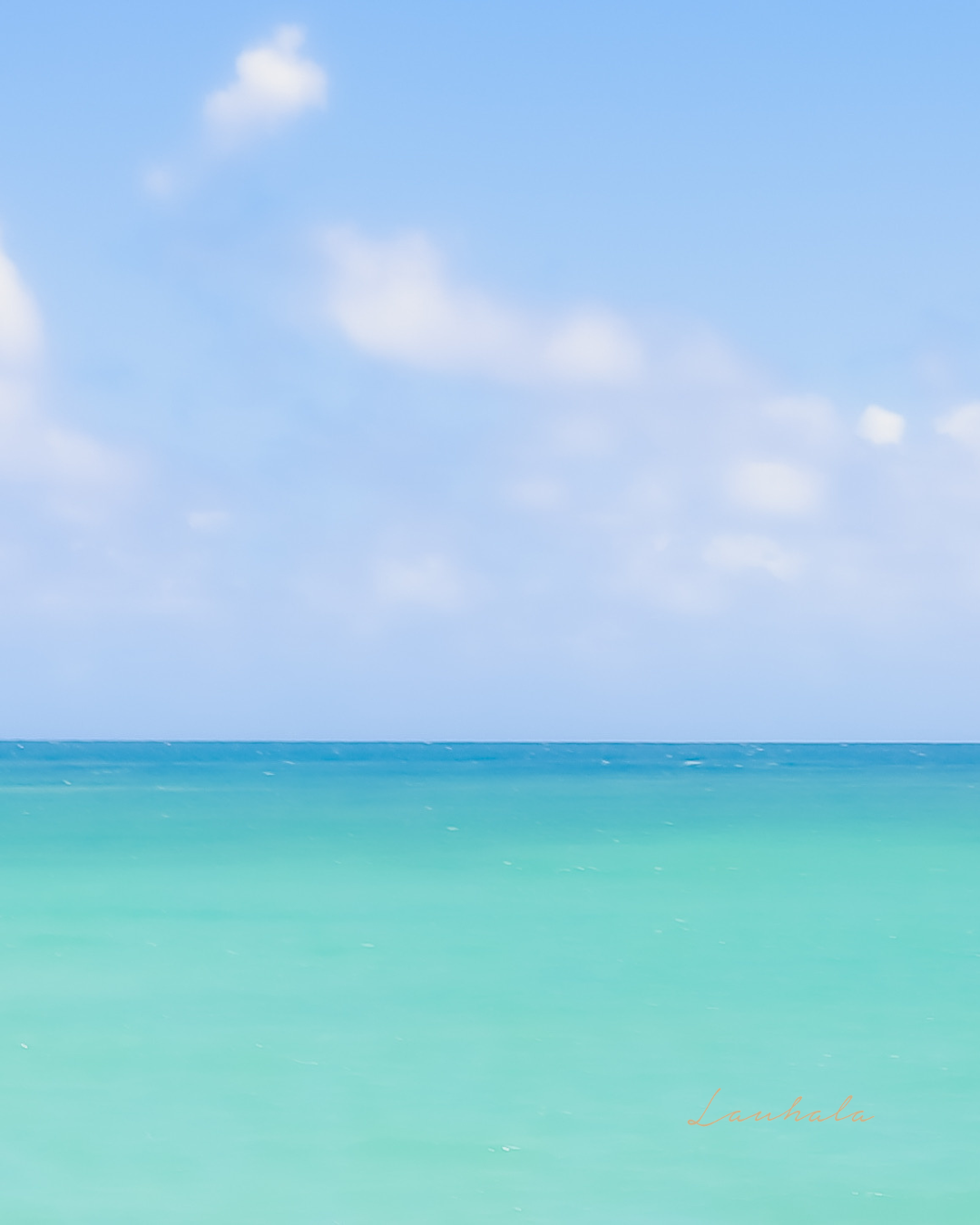 Serene turquoise ocean waters meet blue sky with scattered white clouds.