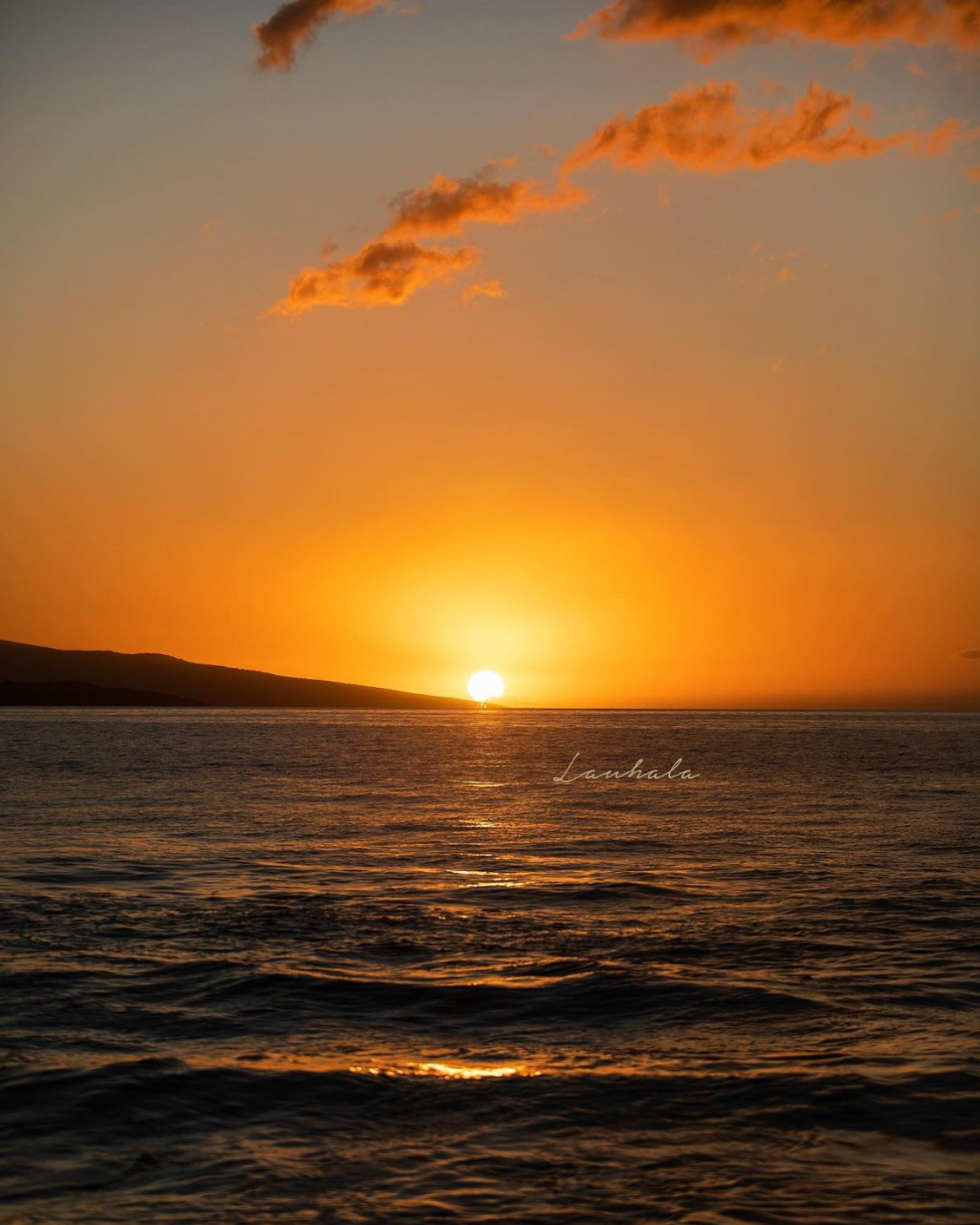 Dramatic orange sunset over ocean horizon with glowing clouds and dark waters.