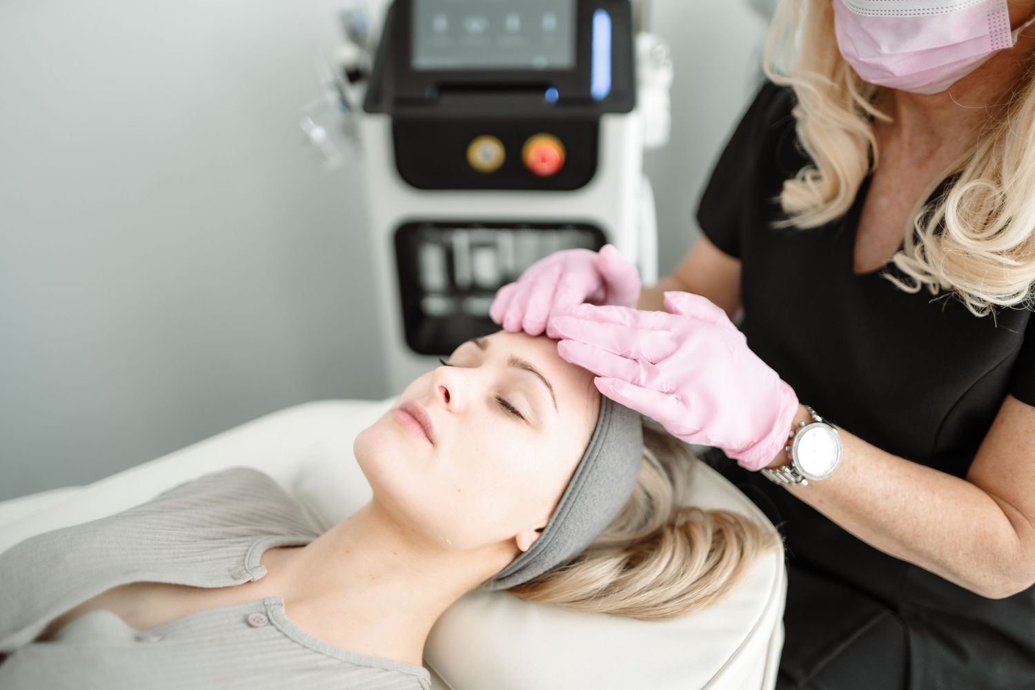 Professional beautician performing facial treatment on client in medical spa setting.