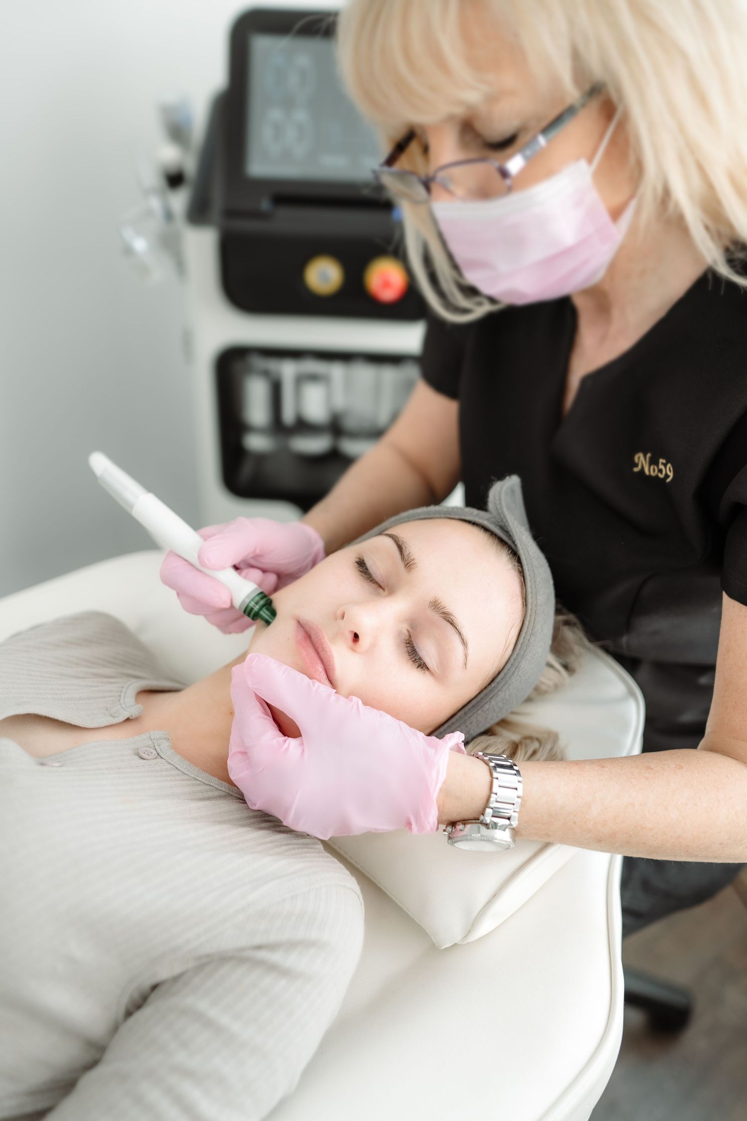 Cosmetic treatment being performed by professional wearing protective mask and gloves.