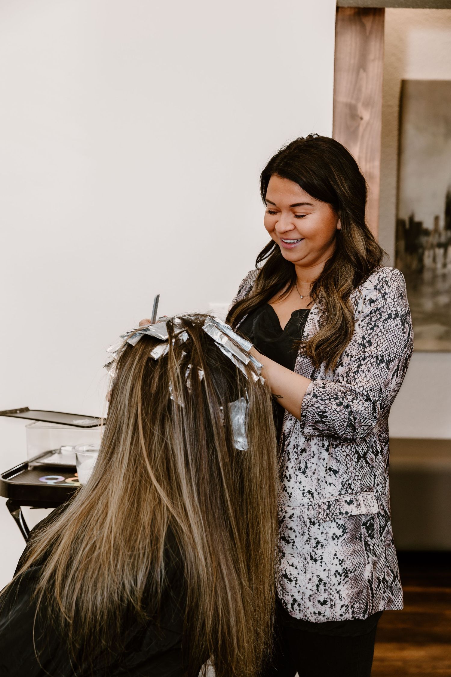 A hairstylist applying color to client's hair in sections with foils.