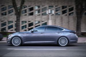 Grey luxury sedan photographed in motion on city street.