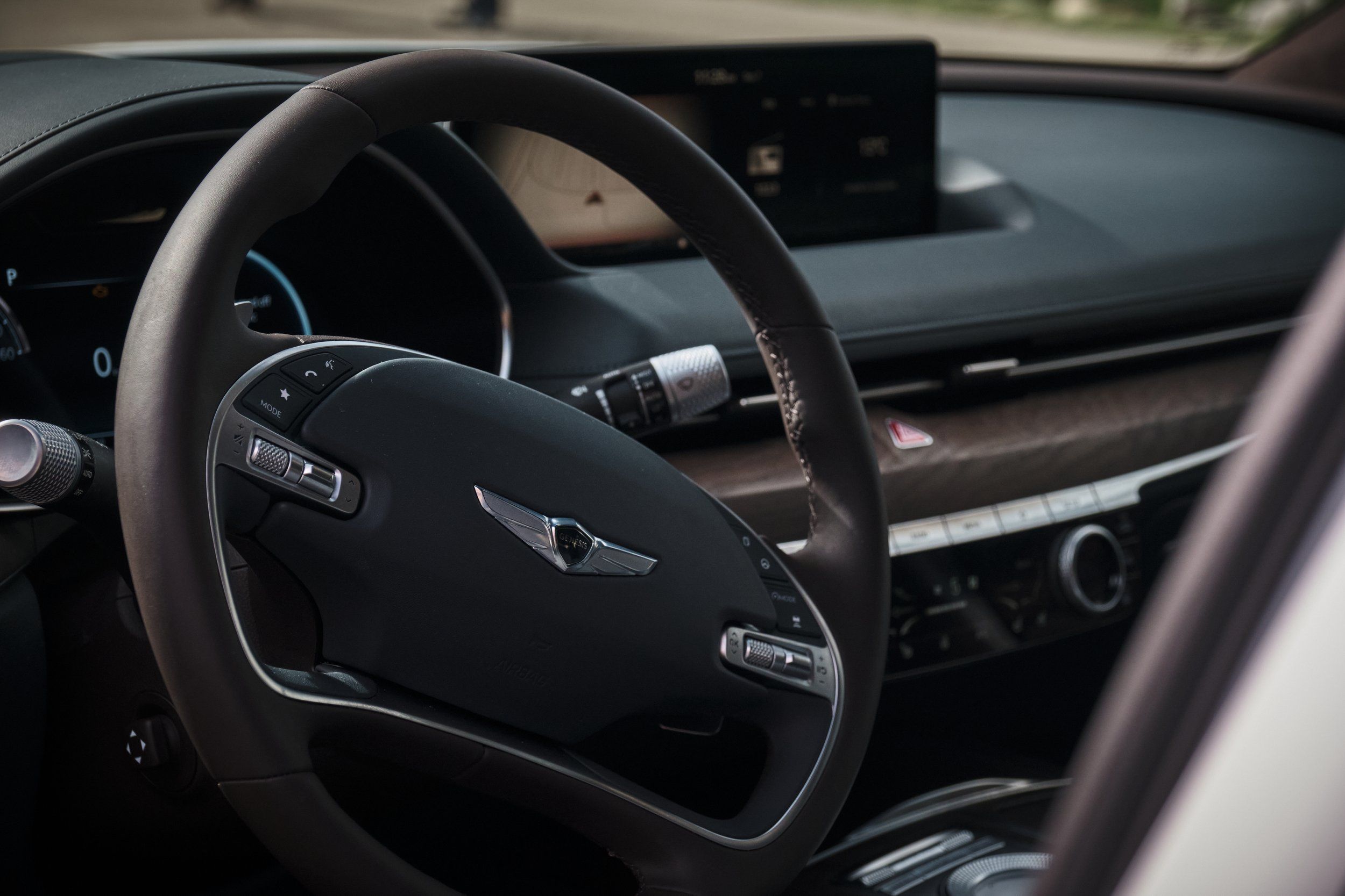 Close-up of Genesis luxury car steering wheel and dashboard interior.