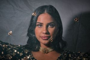 Portrait in moody lighting with gold butterfly decorations and ornate jewelry.