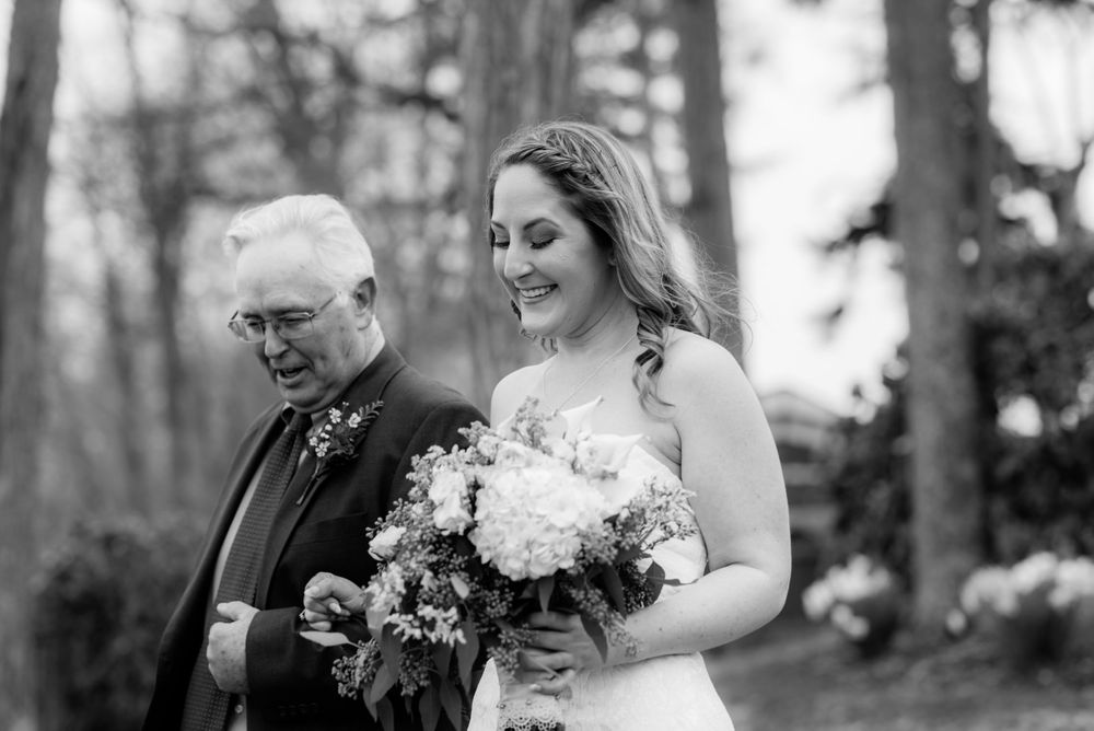 Black and white photo captures a tender moment during a forest wedding ceremony.