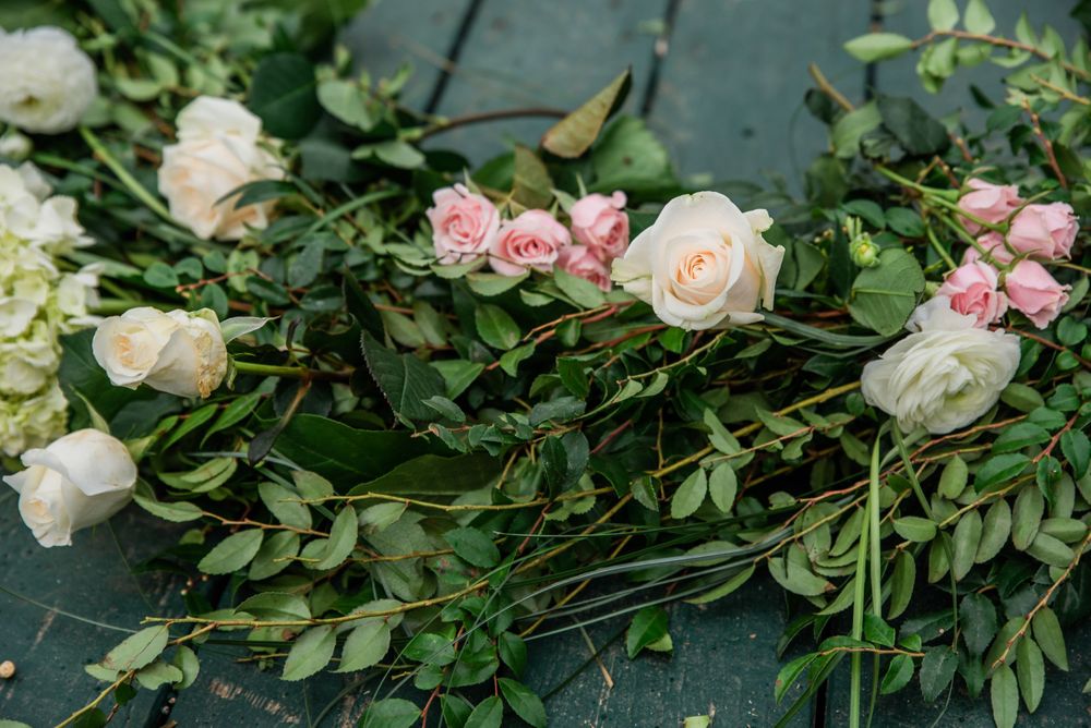 Pink and white roses with green foliage arranged on a teal wooden deck.