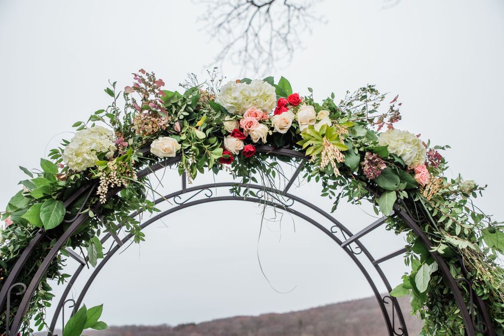 A close-up of a wedding arch decorated with pink and white flowers against a winter landscape.