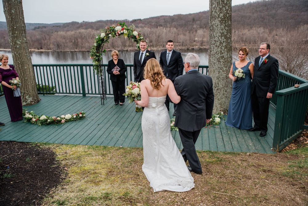 A couple walks down the aisle during their outdoor lakeside deck wedding ceremony.