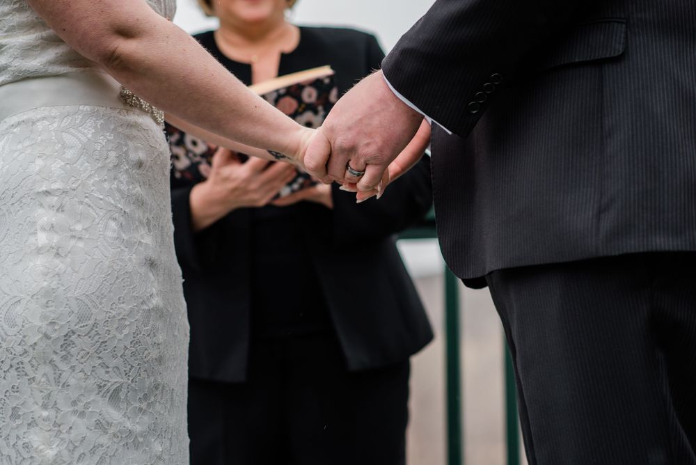 Detail shot of hands clasped together during a wedding ceremony.
