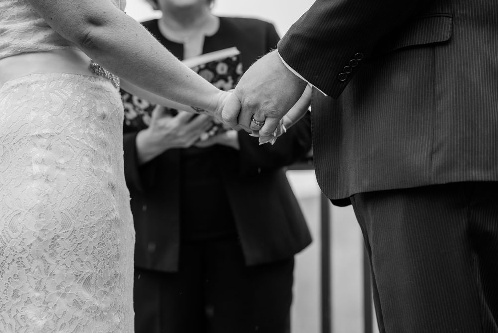 Black and white close-up of hands joined during a wedding ceremony.