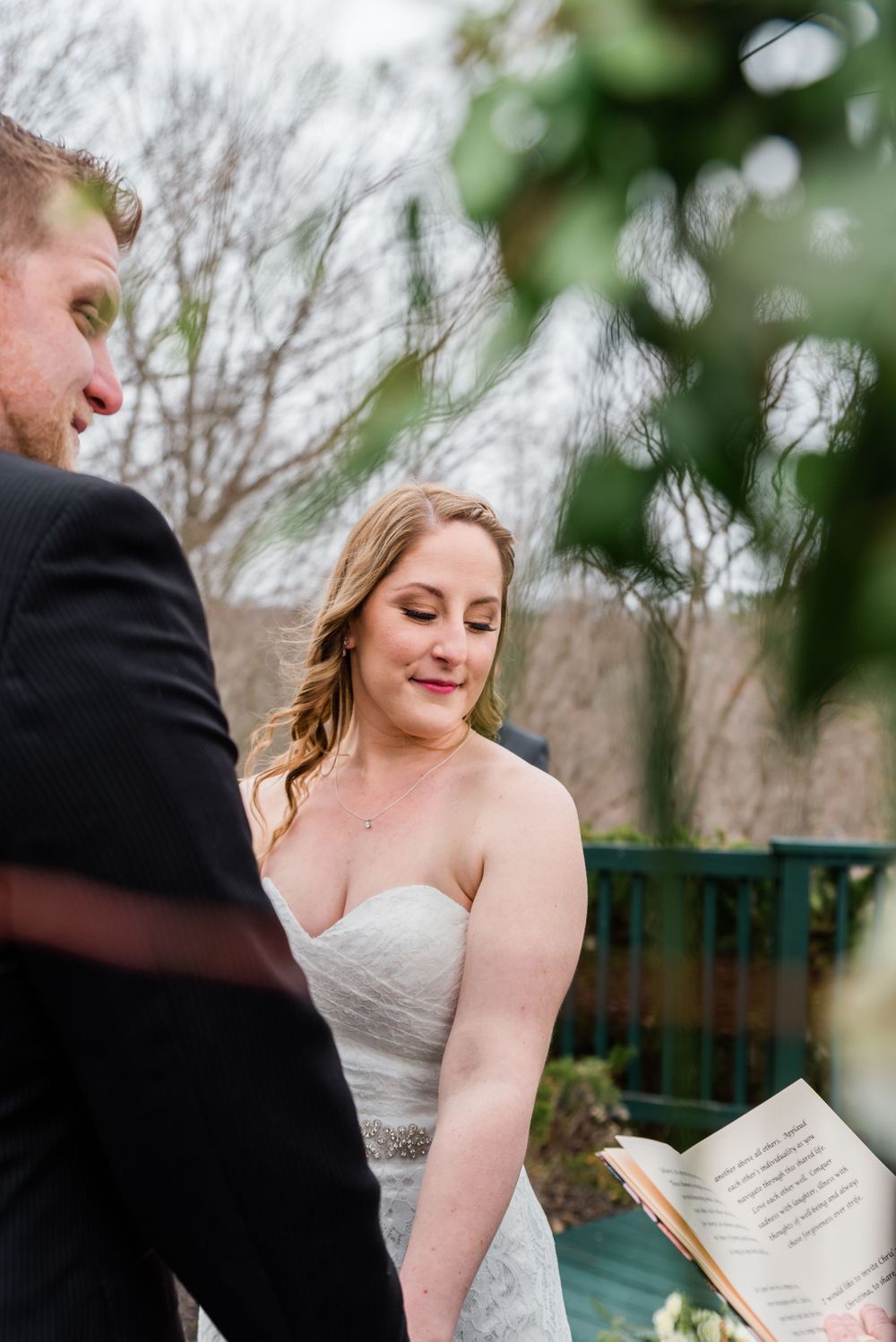 An intimate moment during wedding vows with greenery in the foreground.