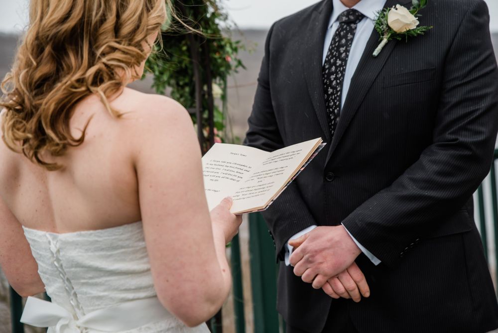 Close-up shot of wedding ceremony details with floral arch in background.