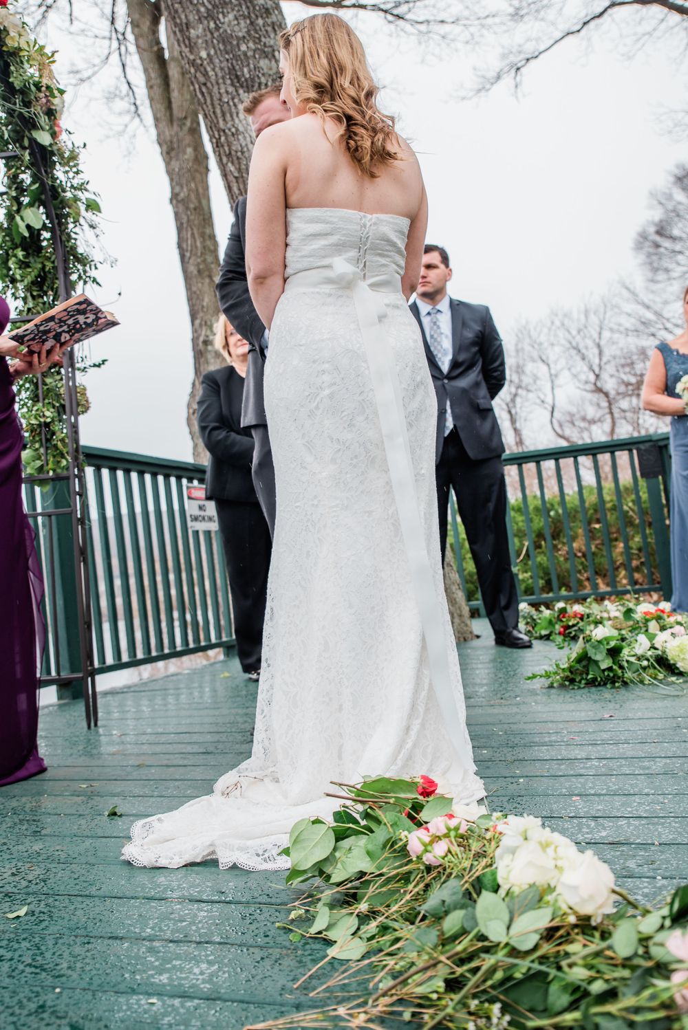 White wedding gown with train and floral decorations on teal wooden deck.