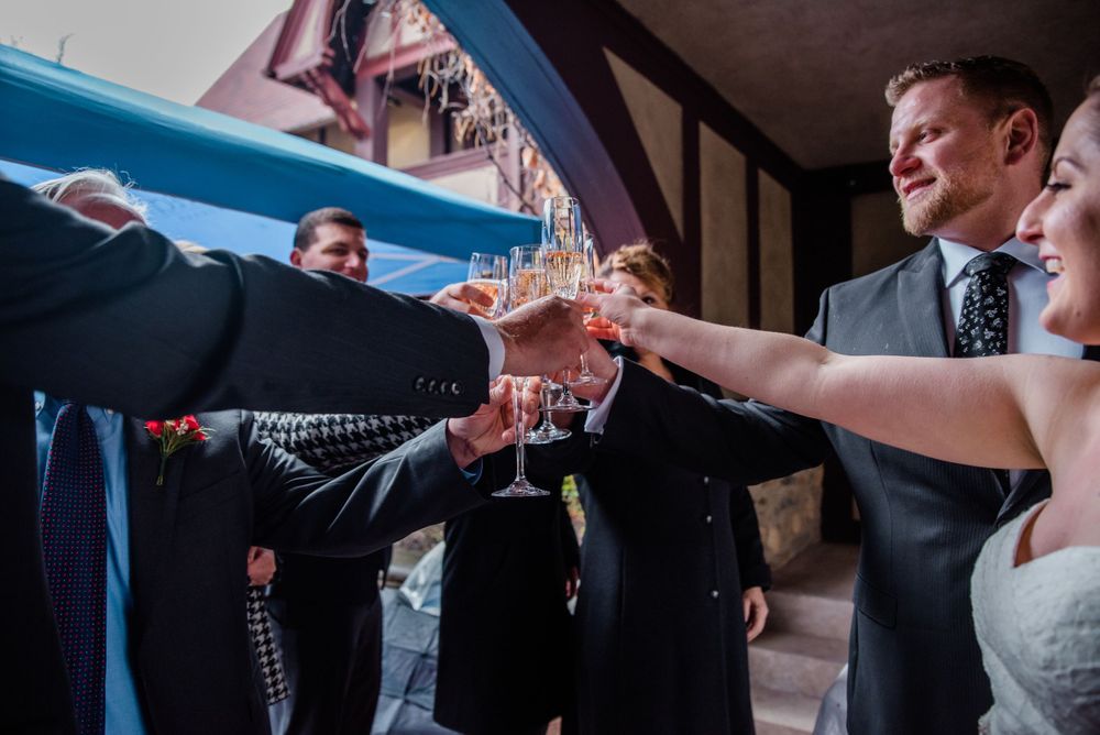 Wedding guests raise champagne glasses in a celebratory toast at an elegant indoor venue.